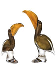 Two glass toucan figurines with large yellow beaks on a white background