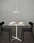 Modern dining setup with a white table and black chairs against a gray wall.