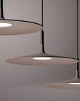 Modern pendant light fixture with three round shades on a neutral background