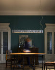 Dining room with wooden table and chairs, dark green walls, and a pendant light.