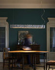 Dining room with wooden table and chairs, dark green walls, and a pendant light.