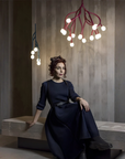 Woman in a dark dress sitting on a bench with modern chandeliers hanging above.