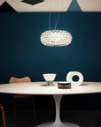 Modern dining room with a round table, chairs, and a hanging light fixture against a dark blue wall.