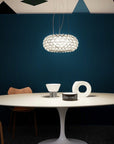 Modern dining room with a round table, chairs, and a hanging light fixture against a dark blue wall.