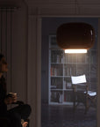 Person sitting in a dimly lit room with a bookshelf in the background