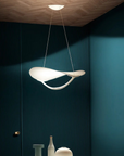 Modern pendant light hanging in a room with dark blue walls and decorative items on a table.