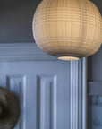 Round woven pendant light hanging against a neutral wall.
