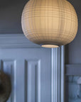 Round woven pendant light hanging against a neutral wall.