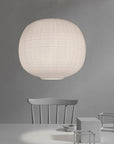 White spherical pendant lamp hanging above a minimalist table and chairs against a gray background