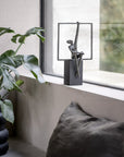 Decorative sculpture on a windowsill with a plant and cushions in the foreground.