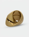 Close up of gold finish sculpture with a unique design on a light gray background