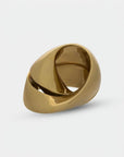 Close up of gold finish sculpture with a unique design on a light gray background