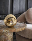 Gold decorative brass sculpture on a marble side table with a sofa in the background