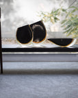 A Gardeco Cance 160 Black Amber sits on a bench in front of a window.