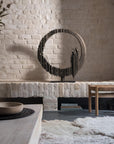 Decorative metal sculpture on a stone shelf with a rustic interior setting.