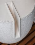 Close-up of a white ceramic object with a textured surface on a wooden surface.