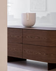 Wooden dresser with the Clausa Forma sculpture from Gardeco on top against a white wall.