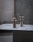 Two stone sculptures on a marble surface with a gray concrete wall background
