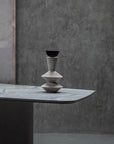 Stack of stone vases on a gray surface with a textured wall background
