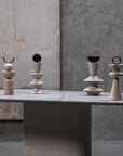 Set of five stone-like sculptures on a gray surface with a concrete wall background
