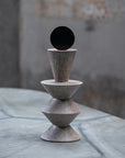 Stack of three stone-like geometric shapes on a textured surface with a blurred background