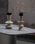 Two geometric stone sculptures on a marble surface with a rustic background