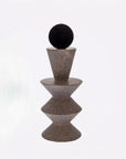 Decorative object with a black sphere on top of a textured brown pyramid structure against a white background