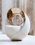 Decorative sculpture with gold and white design on a neutral background