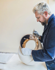 Man working on a ceramic piece with gold finish bronze inlay