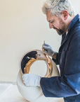 Man working on a ceramic piece with gold finish bronze inlay