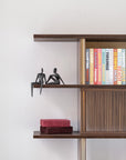 Wooden bookshelf with Assouline travel series cofffee table books & bronze sculptures from Gardeco against a white wall