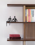 Wooden bookshelf with Assouline travel series cofffee table books & bronze sculptures from Gardeco against a white wall