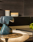 Decorative blue green patina finish bronze sculpture on a table in a modern interior setting