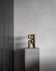 Bronze sculpture on a gray pedestal against a gray wall