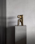 Bronze sculpture on a gray pedestal against a gray wall