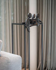 Decorative sculpture of three figures on a stand in a living room setting with curtains and a sofa.