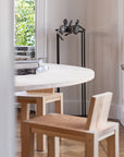 Dining area with a round white table and wooden chairs near a window and bronze sculpture of 3 men called Let's talk from Gardeco