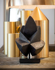 Decorative black sculpture on a wooden surface with gold lamp in the background