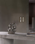 Metallic sculpture on a concrete surface with a neutral background