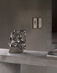 Metallic sculpture on a concrete surface with a neutral background