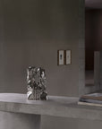 Silver abstract sculpture on a concrete surface with a neutral background