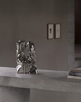 Silver abstract sculpture on a concrete surface with a neutral background