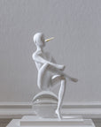 White sculpture - The Pinochhio from Gardeco on a clear sphere against a plain wall.