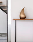 Modern interior with a gold sculpture on a wooden shelf next to a staircase.