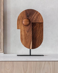 Wooden sculpture on a stand against a light wall