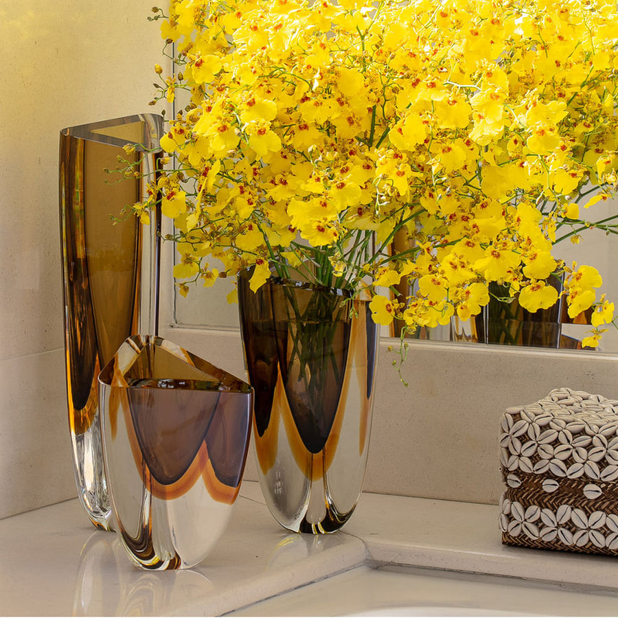 A Gardeco Glass Vase Triangle 3 Fume Amber with yellow flowers.