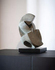 Abstract bronze sculpture on a black base against a neutral background