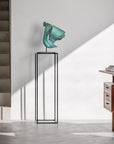 Modern interior with a green sculpture on a black stand and wooden furniture.