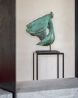 Bronze sculpture on a stand against a neutral wall