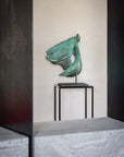 Bronze sculpture on a stand against a neutral wall
